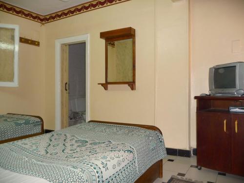 开罗金星旅馆的一间卧室配有一张床、一台电视和一个梳妆台