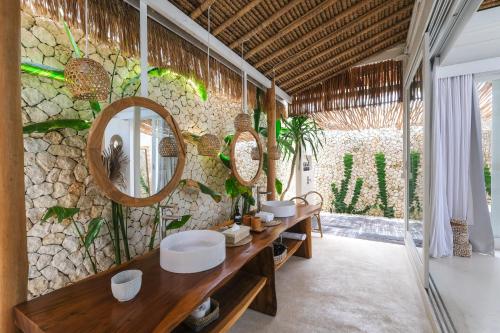 乌鲁瓦图Amaka Villas的浴室设有两个水槽和石墙镜子。