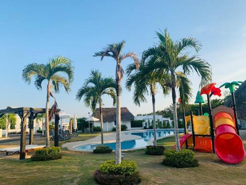 里奥阿托Enjoy a beautiful beach house in Panamá的一个带滑梯和棕榈树的游泳池的度假酒店