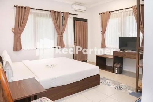 巴图Panorama İnn Residence Batu Mitra RedDoorz的一间卧室配有一张床、一张书桌和一台电视