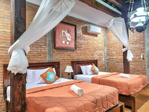 日惹纳尔姆苏月萨托诺旅馆的一间卧室设有两张床和砖墙