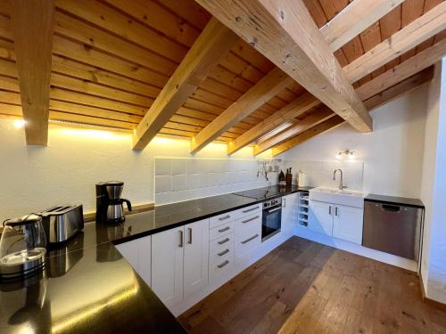 普夫龙滕Chalet Alpenflair的一间设有白色橱柜和木制天花板的大厨房