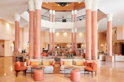 马拉喀什Iberostar Club Palmeraie Marrakech All Inclusive的大厅,大楼内摆放着橙色椅子和桌子