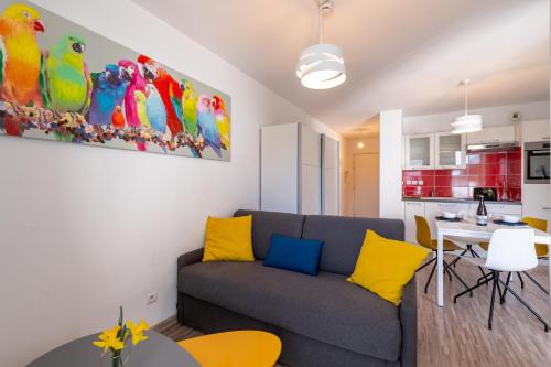 托农莱班Studio Cosy les Perruches的客厅配有灰色的沙发和黄色的枕头。