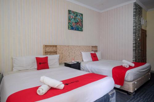 日惹RedDoorz at Mamagayo Inn Yogyakarta的酒店客房带两张红色和白色的床单