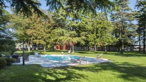 Chiópris-Viscone奇奥里奇别墅 的庭院内的游泳池,带椅子和树木