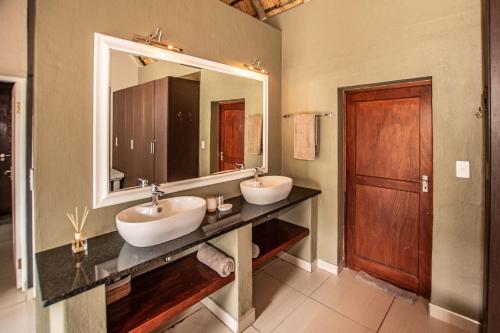 侯斯普瑞特Leopard's Lair Bush Lodge的一间带两个盥洗盆和大镜子的浴室