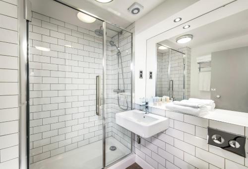 格拉斯哥Glasgow West Hotel by Compass Hospitality的白色的浴室设有水槽和淋浴。