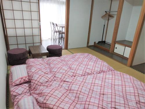 阿苏市Guest House Asora的一间卧室配有一张带粉红色条纹毯子的床