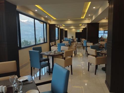 吉尔吉特Avari Xpress Gilgit的用餐室设有桌椅和窗户。