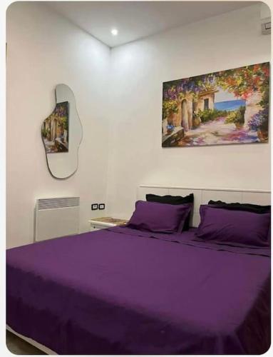 Sidi DaoudAppartement Cosy aux Jardins de Carthage的一间卧室配有一张紫色床,墙上挂有绘画作品