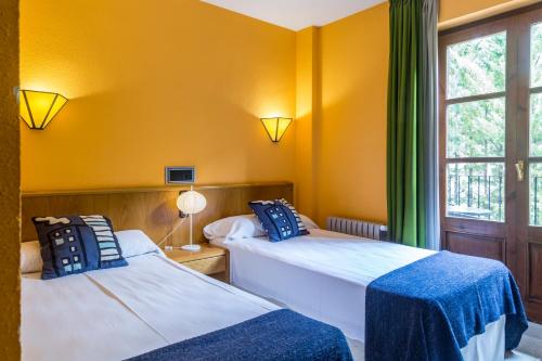 贝纳斯克圣安东贝纳斯克酒店的配有两张床的客房,设有黄色的墙壁和窗户