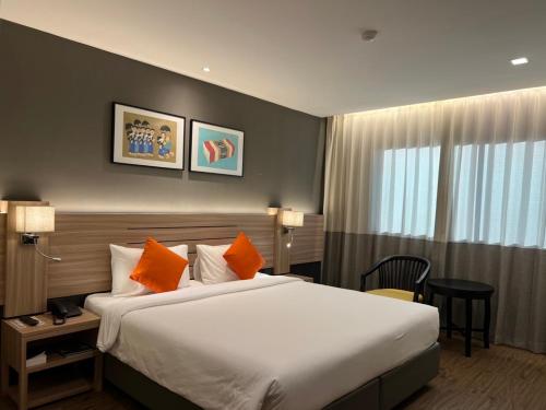 坤敬Le cassia Hotel的酒店客房配有一张带橙色枕头的大床
