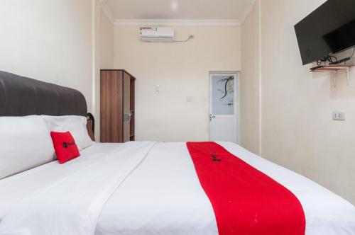 先达RedDoorz at Samuel Homestay Pematangsiantar的卧室配有白色的床和红色毯子
