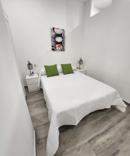卡塔赫纳Green Apartamentos Cartagena的白色卧室配有带绿色枕头的大型白色床