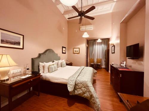 加尔各答The Elgin Fairlawn, Kolkata的一间卧室配有一张床、一张桌子和吊扇