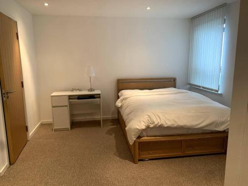 利兹Large Private Flat in City Centre Leeds的一间卧室配有一张床、一张书桌和一个窗户。