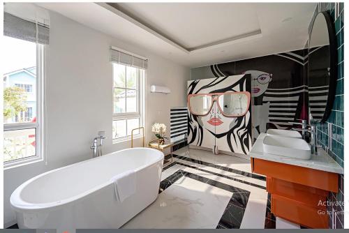 潘切Novaworld Villas的带浴缸的浴室和一幅女子画