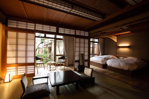 丰冈市城崎温泉 旅館 つばき乃 - Kinosaki Onsen Ryokan Tsubakino的卧室配有一张床和一张桌子及椅子