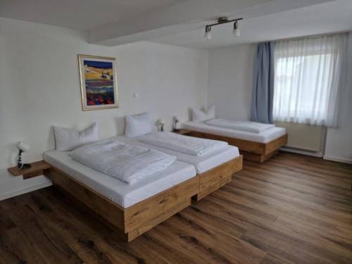 新乌尔姆索耐科勒酒店的铺有木地板的客房内的两张床