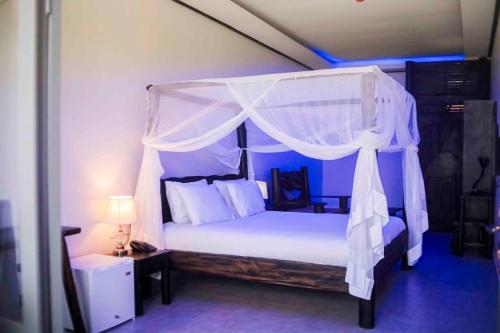 KaragariKingfisher Resort-Muhazi的卧室配有白色的天蓬床和灯