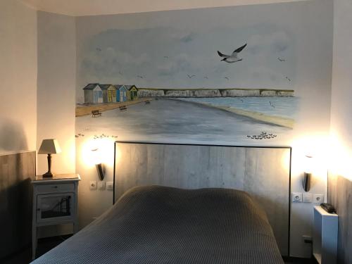 滨海卡约Logis - Le Neptune Hôtel & Restaurant的卧室配有海滩上的大画作