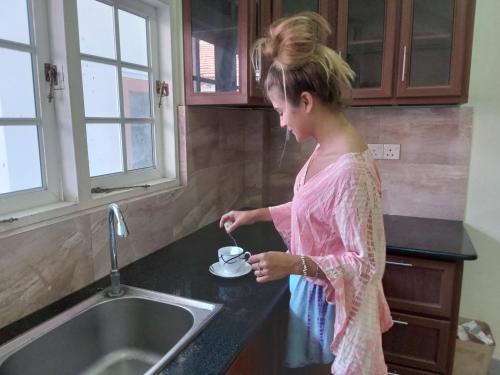 尼甘布Cross Ceylon的站在厨房里,从杯子里喝一杯的年轻女孩