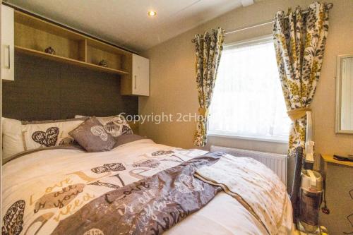 洛斯托夫特Brilliant Caravan With A Partial Sea View In Suffolk Ref 32026az的一间卧室设有一张大床和一个窗户。