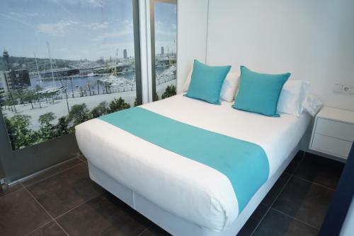 巴塞罗那巴塞罗那54酒店的窗户客房内的白色床和蓝色枕头