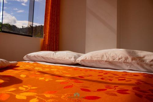PillcopataHinkiori Inn - Hotel Manu的两张白色枕头和橙色毯子,床上