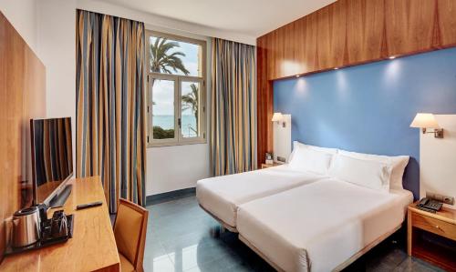 锡切斯Sercotel Kalma Sitges的酒店客房,设有床铺和蓝色的墙壁