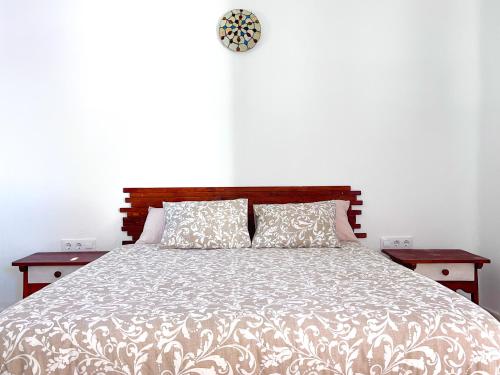 奇克拉纳－德拉弗龙特拉La Casita de Los Alambiques的一间卧室配有一张带两张桌子和闹钟的床