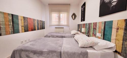 莱昂www Goyahospitales es的配有两张单人床的客房,墙上挂有绘画作品