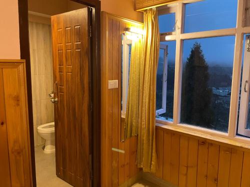 拉冲Montanamar Lachung的通往带卫生间和窗户的浴室的开放式门