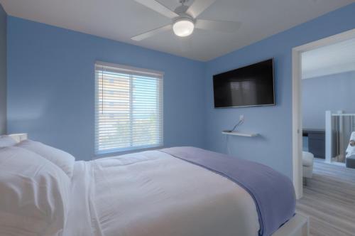 杰克逊维尔海滩A Wave From It All Oceanview 2nd Level Patio的蓝色卧室配有一张带吊扇的床