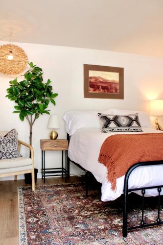 埃斯蒂斯帕克Kinnikinnik Motor Lodge的一间卧室配有一张床、一个植物和椅子