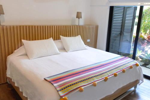 EscazúColina Inn的一张带两个枕头的白色床和彩虹毯子