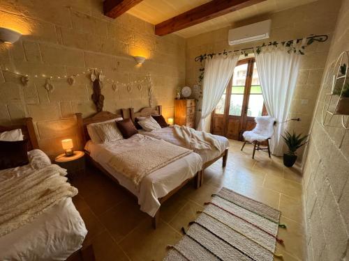 萨奈特Tal-Mans Farmhouse Gozo的一间卧室设有两张床和大窗户