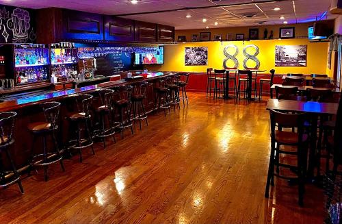 BuckhannonBicentennial Inn的一间酒吧,铺有木地板,并在一间客房内设有酒吧凳子