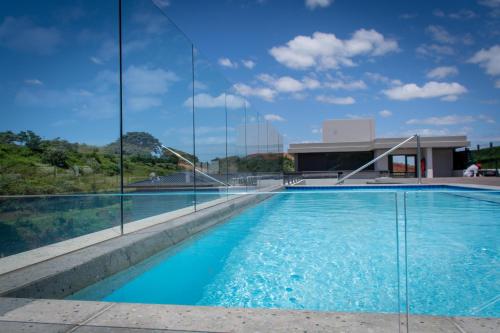 巴利托Zimbali Lakes Boulevard Suites的一座带玻璃墙的建筑前的游泳池