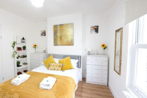 剑桥King's Central Cambridge Apartment的白色卧室配有一张带黄色枕头的大床