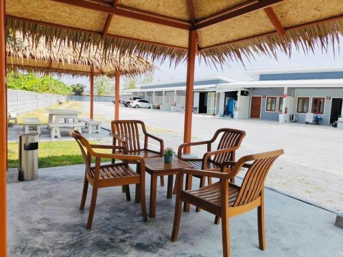 Ban Noen Makokสราญรัตน์รีสอร์ท的草伞下的一张木桌和椅子