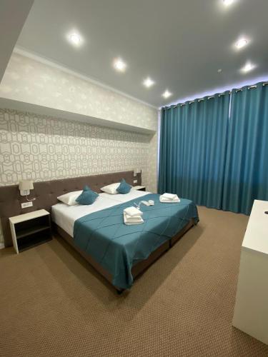 库斯塔奈De Marco Hotel的一间卧室配有一张带蓝色窗帘的大床