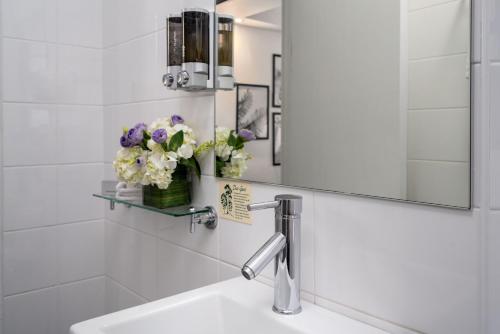 悉尼柏伟诗城市中心酒店的浴室设有水槽、镜子和鲜花