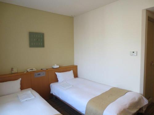 熊本熊本内斯特酒店的一间设有两张床的客房和墙上的时钟