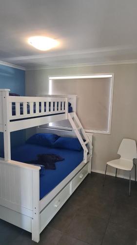 科夫斯港香蕉海岸大篷车公园酒店的配有椅子的客房内的一张白色双层床