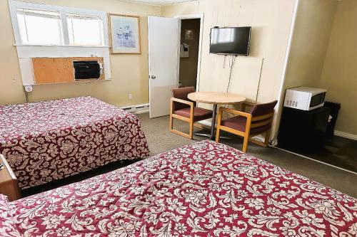 艾恩伍德Love Hotels Timberline at Lake Superior MI的酒店客房设有两张床、一张桌子和电视。