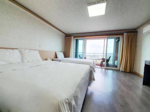 济州市济州海洋家庭酒店的酒店客房设有两张床和大窗户。