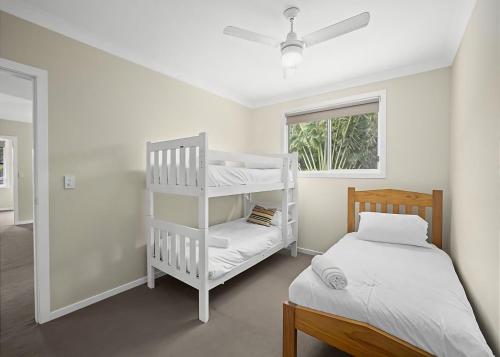 萨维特尔Sawtell Swells的一间卧室配有双层床、白色的床和窗户。