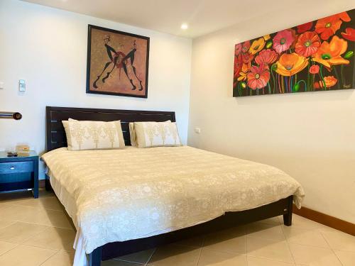 芭东海滩Andaman Hill Pool Seaview的卧室配有一张床,墙上挂有绘画作品